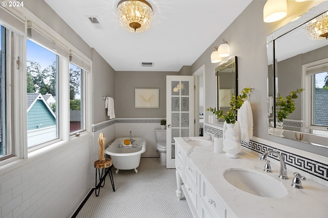 bathroom with a notable chandelier, vanity, toilet, and a bath