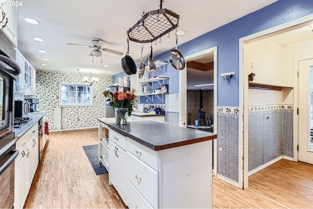 kitchen with white cabinetry, a wood stove, light hardwood / wood-style floors, and a center island