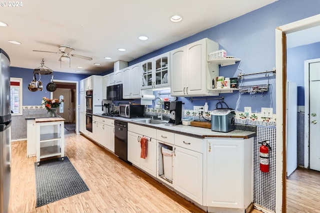 kitchen featuring white cabinets, black appliances, sink, ceiling fan, and light wood-type flooring