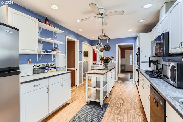 kitchen with butcher block counters, white cabinetry, black appliances, and light hardwood / wood-style flooring