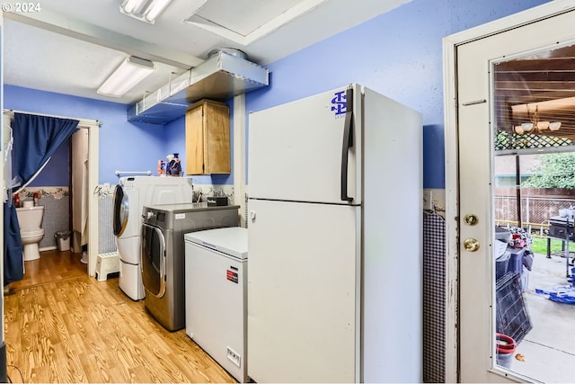 laundry room featuring cabinets, washing machine and clothes dryer, and light hardwood / wood-style flooring