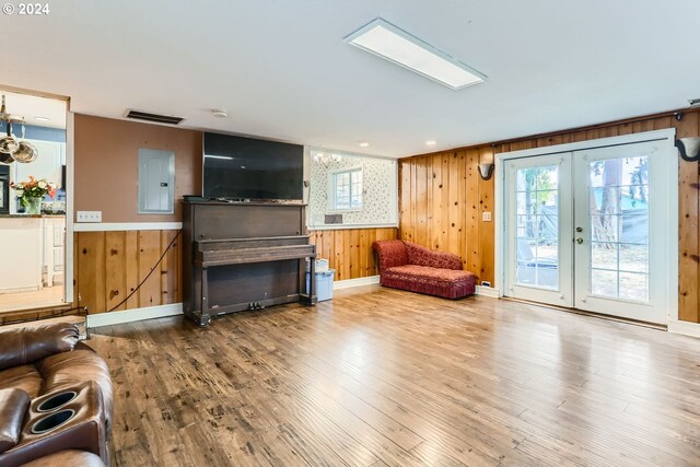 living room featuring french doors, electric panel, wood-type flooring, and wooden walls