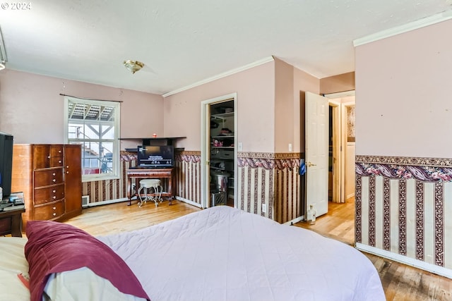 bedroom featuring ornamental molding, light hardwood / wood-style flooring, a spacious closet, and a closet