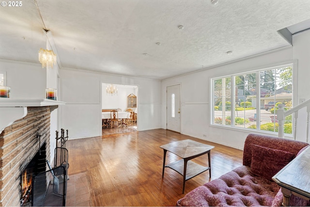living area with a fireplace, crown molding, baseboards, a chandelier, and hardwood / wood-style flooring