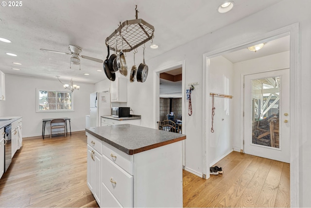 kitchen with stainless steel microwave, dark countertops, freestanding refrigerator, and white cabinets