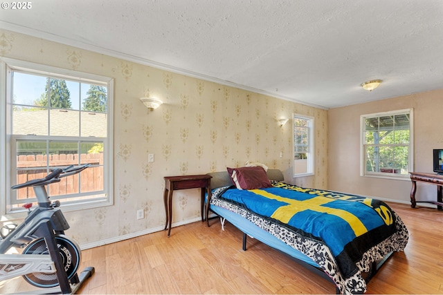 bedroom with wood finished floors, a textured ceiling, and baseboards