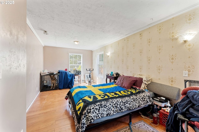 bedroom featuring baseboards, wood finished floors, a textured ceiling, and ornamental molding