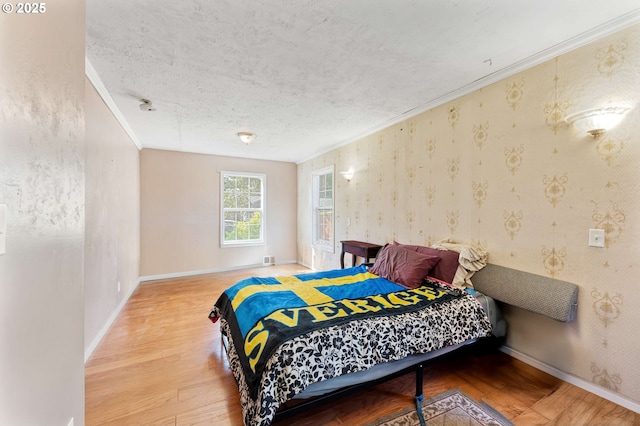 bedroom featuring baseboards, wood finished floors, a textured ceiling, and crown molding