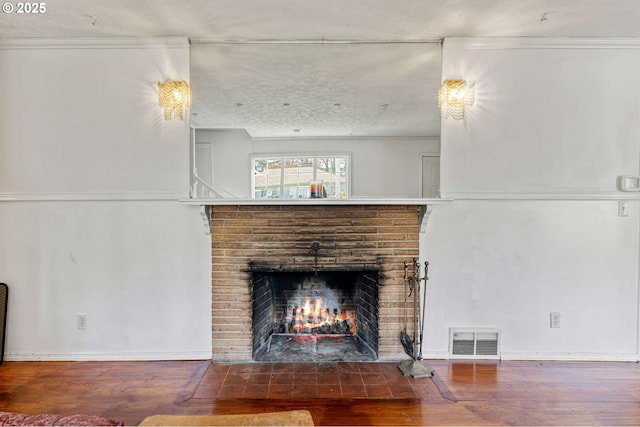 unfurnished living room with baseboards, visible vents, wood finished floors, a fireplace, and ornamental molding
