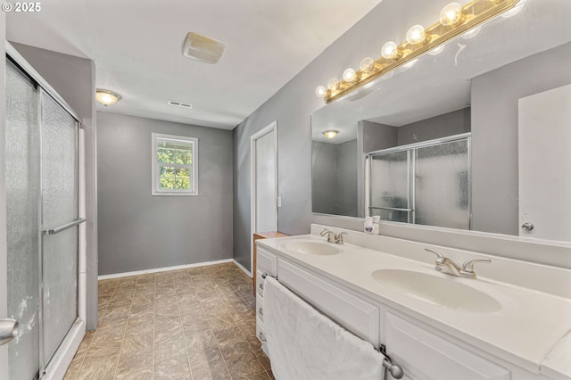 full bathroom with a shower stall, baseboards, a sink, and double vanity
