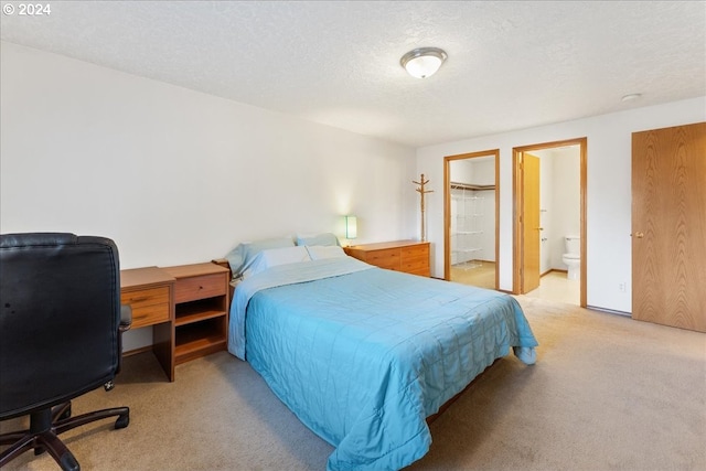 bedroom featuring light carpet, a textured ceiling, and ensuite bath