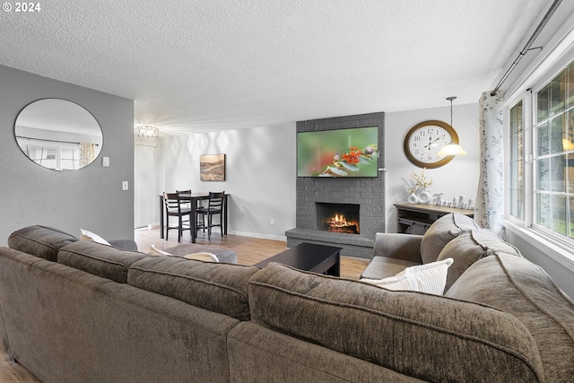 living room with a textured ceiling, light wood-type flooring, and a brick fireplace