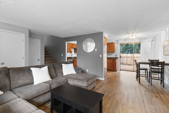 living room featuring light hardwood / wood-style floors, sink, and a textured ceiling