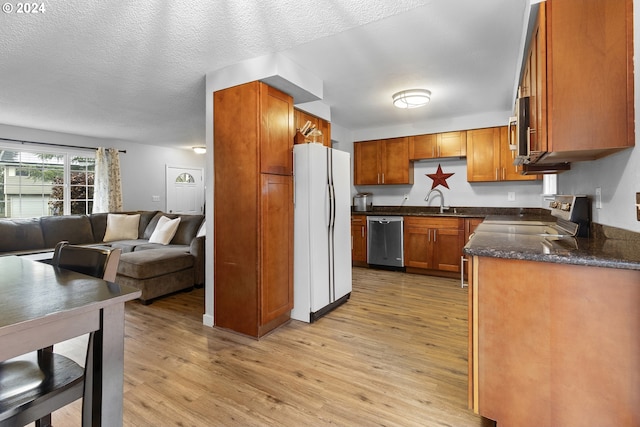 kitchen featuring sink, light wood-type flooring, a textured ceiling, and appliances with stainless steel finishes