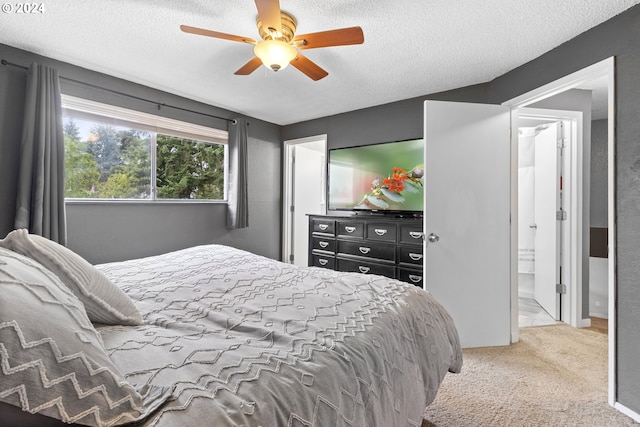 bedroom with ceiling fan, carpet floors, ensuite bathroom, and a textured ceiling