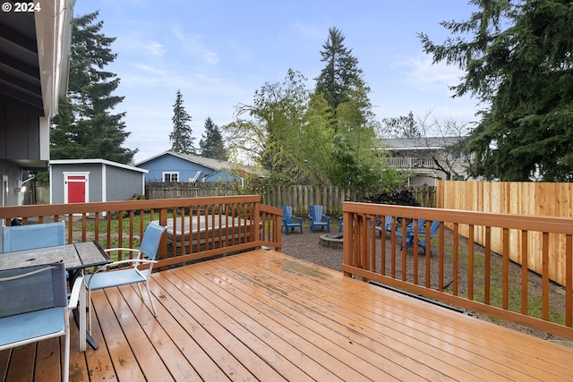 wooden terrace with a fire pit and a storage unit