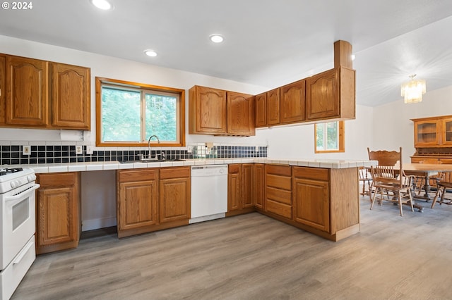 kitchen featuring tile counters, light hardwood / wood-style flooring, kitchen peninsula, sink, and white appliances