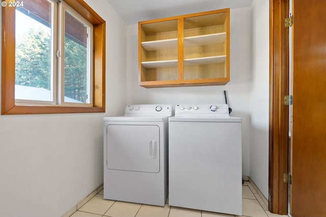 laundry room with independent washer and dryer and light tile patterned floors