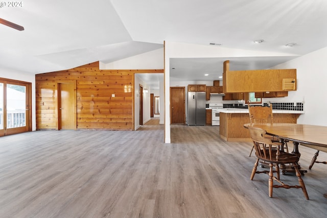 kitchen featuring stainless steel fridge, vaulted ceiling, kitchen peninsula, and light wood-type flooring