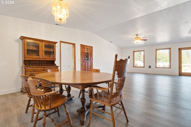 dining area with lofted ceiling, ceiling fan with notable chandelier, and dark hardwood / wood-style flooring