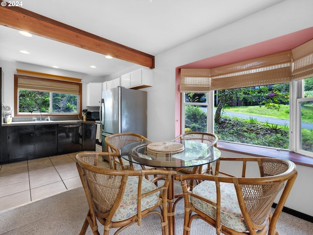 dining area with a healthy amount of sunlight, beamed ceiling, sink, and light tile floors