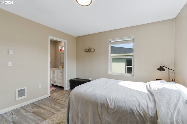 bedroom featuring ensuite bath and light hardwood / wood-style floors