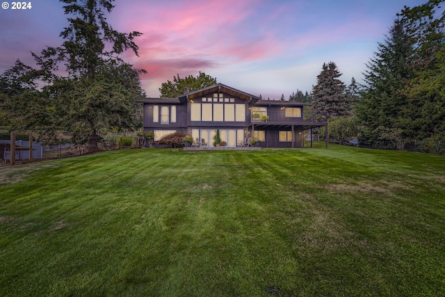 back house at dusk featuring a yard