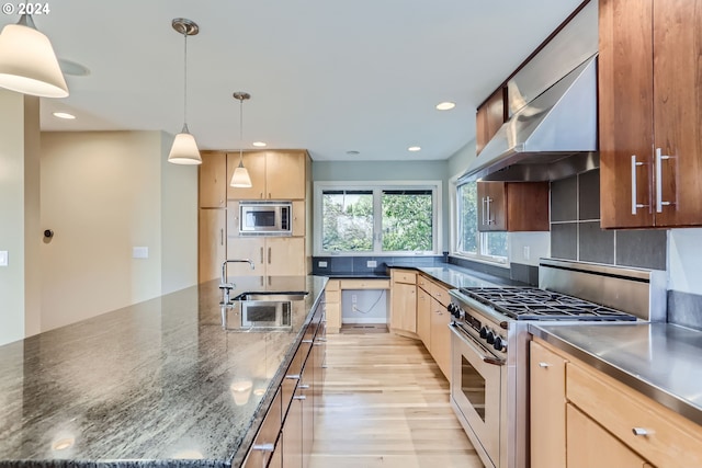 kitchen with sink, wall chimney exhaust hood, stainless steel appliances, backsplash, and pendant lighting