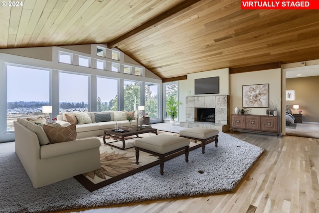 living room featuring a wealth of natural light, a fireplace, lofted ceiling with beams, and light wood-type flooring