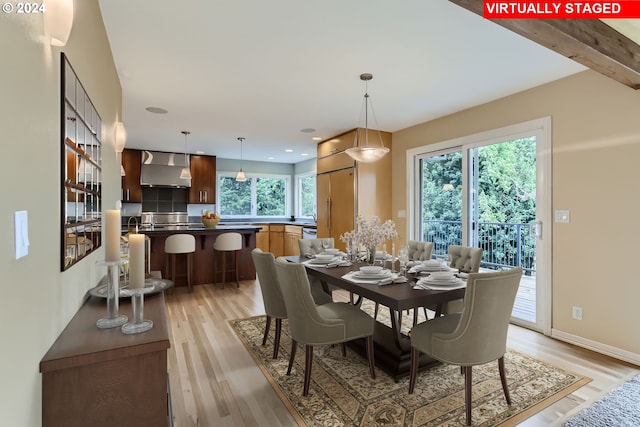 dining area with beamed ceiling, a healthy amount of sunlight, and light hardwood / wood-style floors