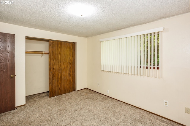 unfurnished bedroom with a textured ceiling, carpet floors, a closet, and baseboards