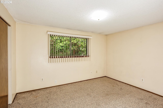 carpeted empty room featuring a textured ceiling and baseboards