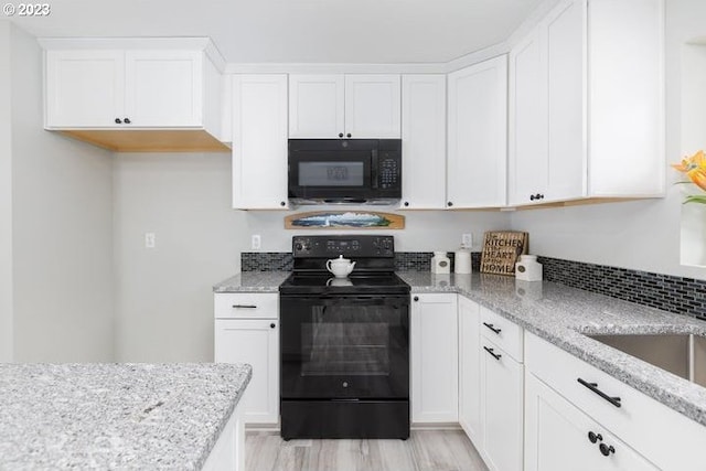 kitchen featuring light stone countertops, white cabinets, black appliances, and light wood-type flooring