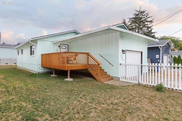 back of house with a garage, a wooden deck, and a lawn