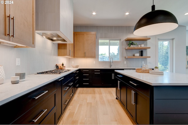 kitchen with light wood-style flooring, a sink, decorative light fixtures, open shelves, and stainless steel gas stovetop