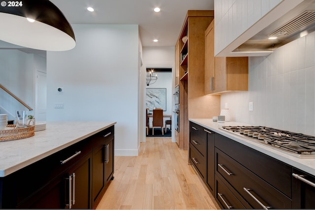 kitchen with light wood finished floors, wall chimney range hood, light stone counters, recessed lighting, and stainless steel appliances