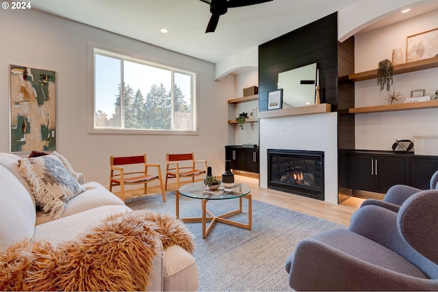 living area featuring recessed lighting, a large fireplace, light wood-style floors, and a ceiling fan