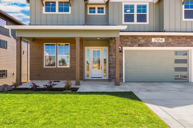 doorway to property featuring a yard, covered porch, board and batten siding, concrete driveway, and an attached garage