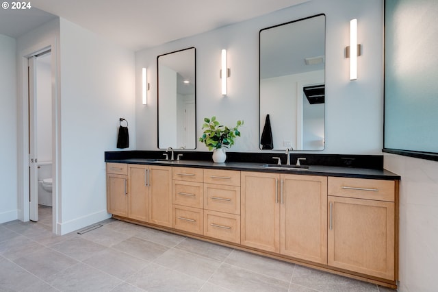 bathroom featuring double vanity, visible vents, toilet, and a sink