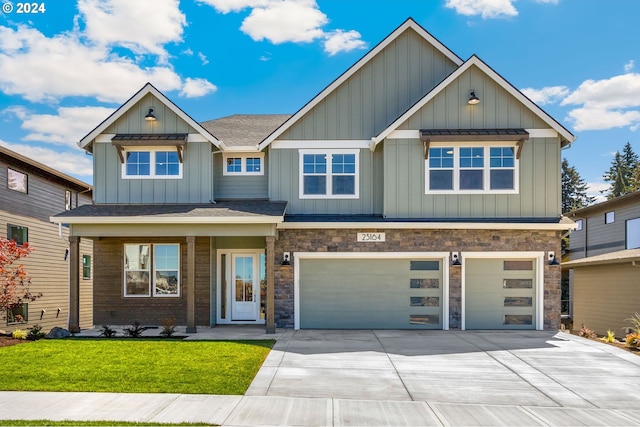 view of front of house featuring a front yard, concrete driveway, a garage, stone siding, and board and batten siding