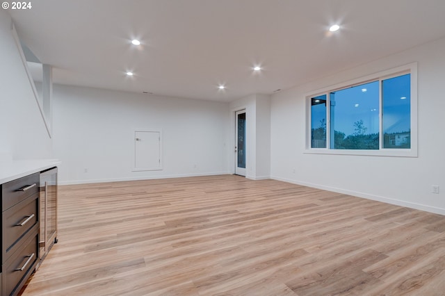 unfurnished living room with recessed lighting, light wood-type flooring, and baseboards