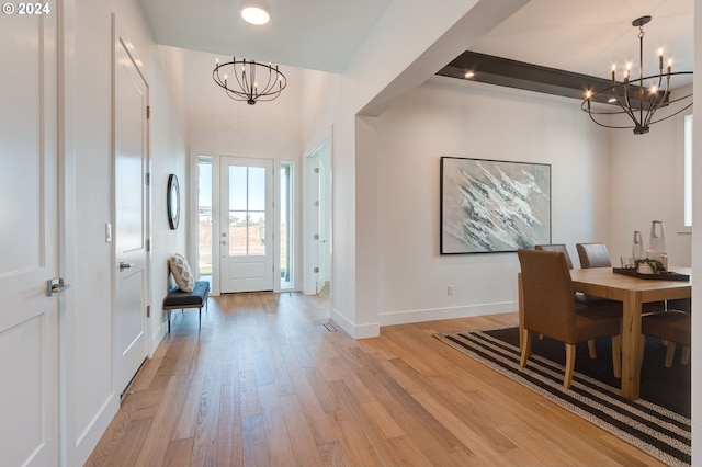 foyer featuring an inviting chandelier, light wood-style flooring, and baseboards