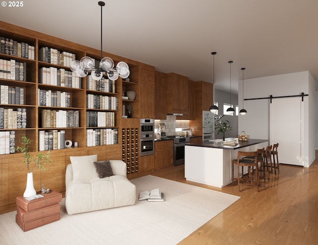 kitchen featuring high end stainless steel range, decorative light fixtures, a barn door, light hardwood / wood-style floors, and backsplash