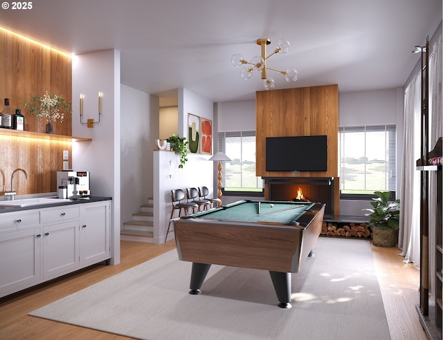 game room featuring pool table, a fireplace, sink, and light wood-type flooring