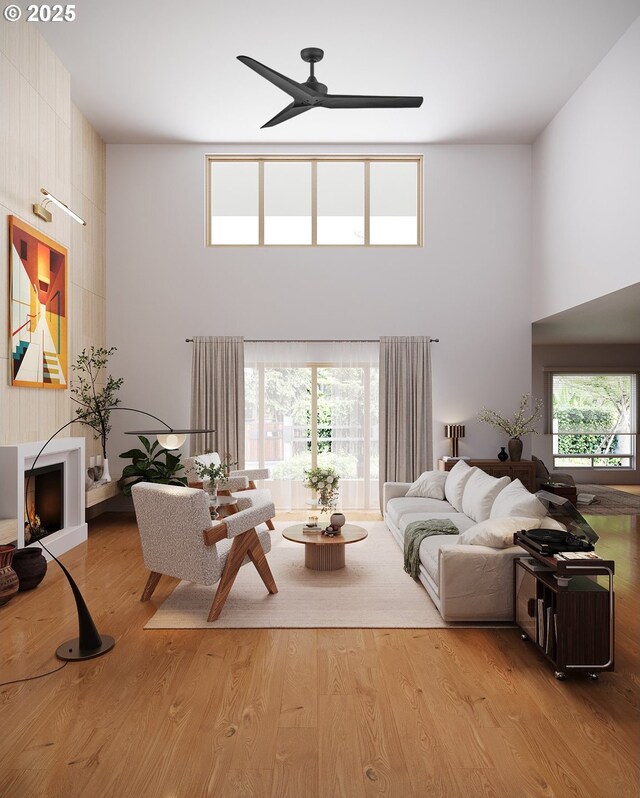 living room featuring a towering ceiling, plenty of natural light, and light hardwood / wood-style flooring