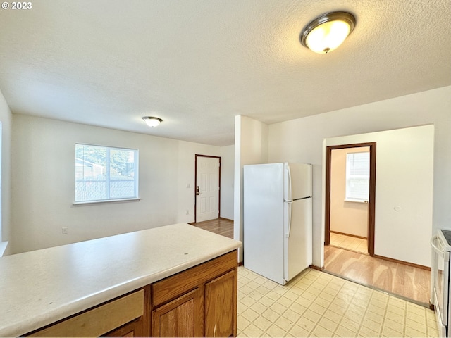 kitchen featuring a textured ceiling, white appliances, and light tile floors