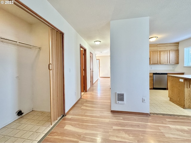 corridor with a textured ceiling and light hardwood / wood-style floors