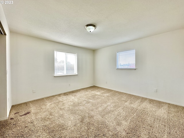 carpeted empty room featuring a textured ceiling