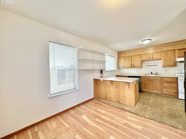 kitchen with white range with electric cooktop, light tile flooring, a breakfast bar area, dishwashing machine, and kitchen peninsula