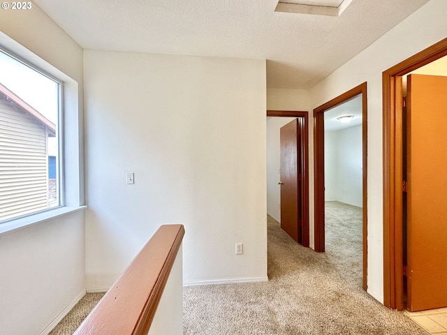 hallway featuring light carpet and a textured ceiling